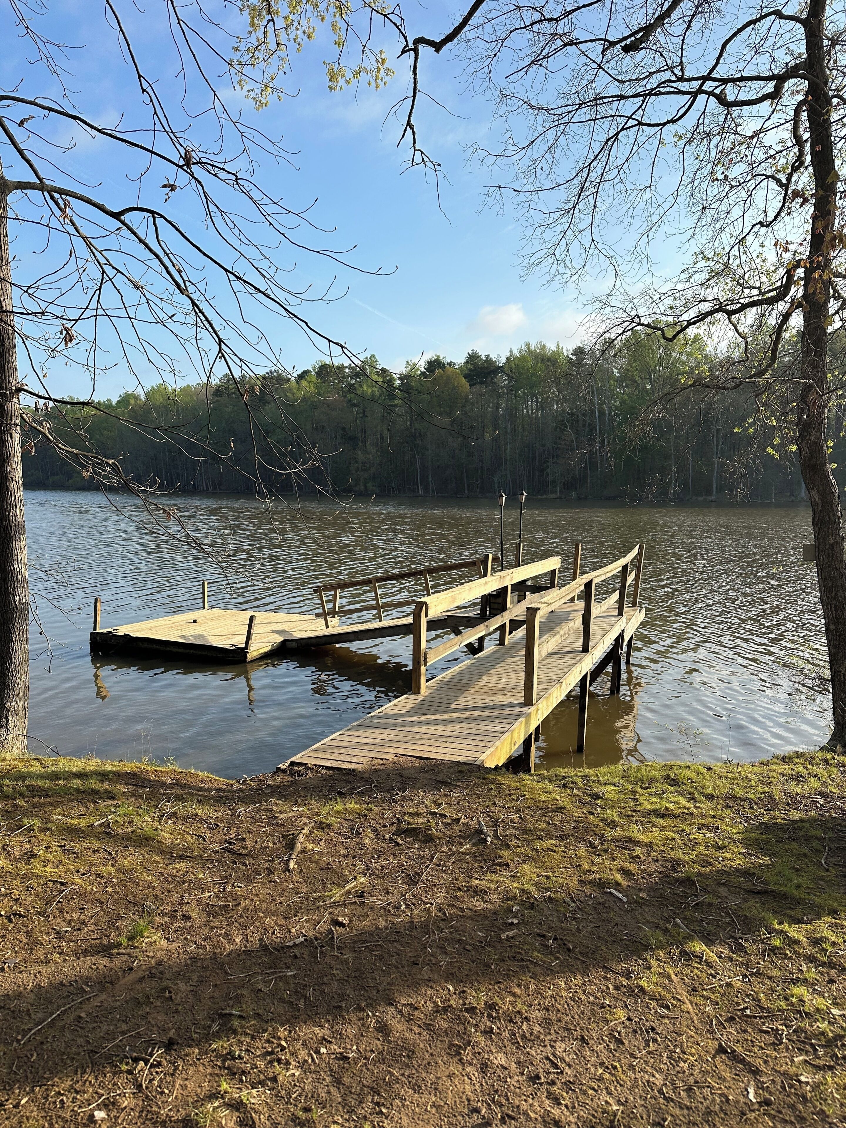 A wooden dock extending into a calm lake surrounded by trees.