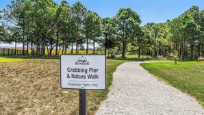 A sign for Crabbing Pier & Nature Walk with a gravel path and trees in the background. - Bayside Retreat | Luxury Resort w/ Pools/Amenities (Berlin)