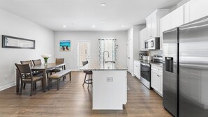A modern kitchen with white cabinets, stainless steel appliances, and a central island. - Bayside Retreat | Luxury Resort w/ Pools/Amenities (Berlin)