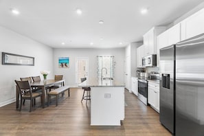 A modern kitchen with white cabinets, stainless steel appliances, and a central island. - Bayside Retreat | Luxury Resort w/ Pools/Amenities (Berlin)