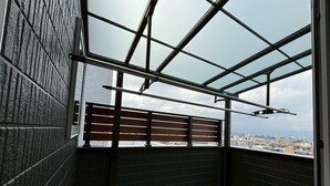 A balcony with a metal railing, a view of the cityscape, and a wooden slatted partition. - Entire House on a Hilltop with Panoramic Views of Fukuoka | 92 ㎡ | A Base for Exploring Fukuoka | Sleeps 8, 2 Parking Spaces (福岡市)