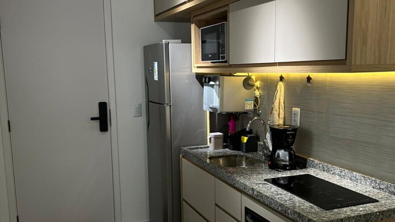 Una cocina compacta con microondas integrado, cafetera y fregadero.