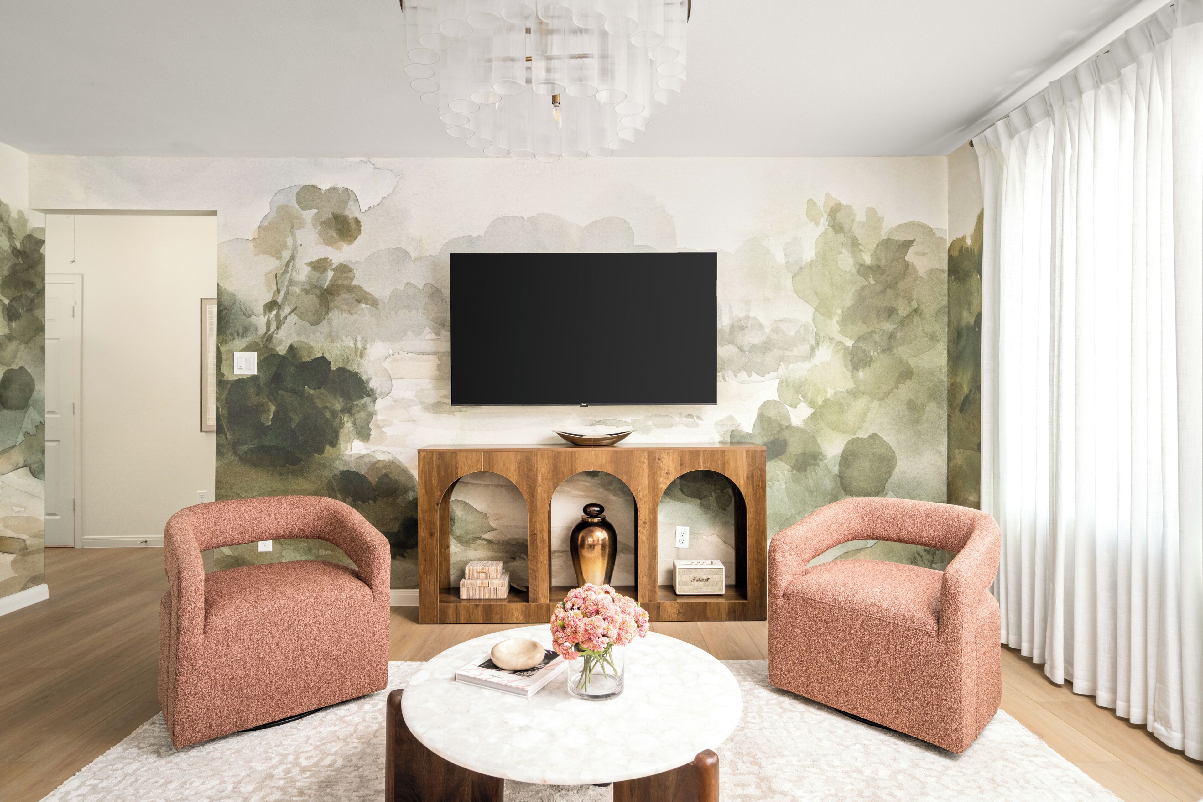 Un salon comprenant un téléviseur, deux fauteuils, une table basse et une cheminée agrémentée d’objets décoratifs.