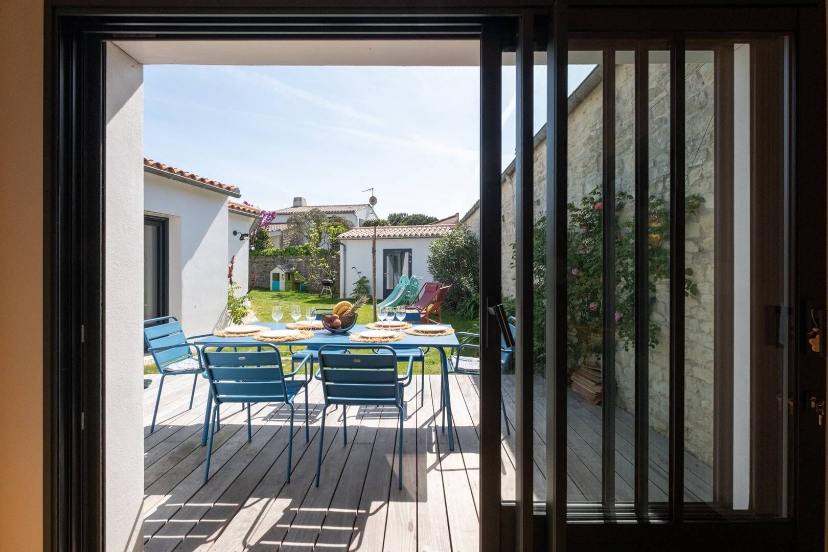 Un patio con tavolo apparecchiato per mangiare, sedie e uno scivolo sullo sfondo.