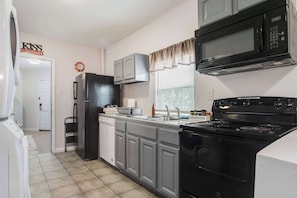 A kitchen with a refrigerator, microwave, stove, and cabinets. - Modern NOLA House with Yard, Your Mardi Gras Base (New Orleans)