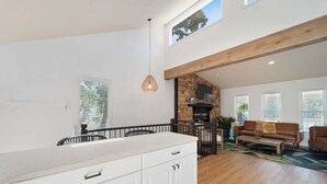 A spacious kitchen with a large island, a stone fireplace, and a high ceiling with exposed beams. - Lake Front |Private Dock |Blue Bungalow|3bed|2bth (Linn Creek)