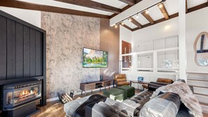 A cozy living room with a fireplace, leather sofa, and a TV mounted on the wall. - Lake View 3BR/2BA in Incline Village, Fireplace (Incline Village)