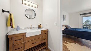 A modern bathroom with a wooden vanity, a round mirror, and a large window. - Lake View 3BR/2BA in Incline Village, Fireplace (Incline Village)