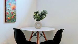 A corner room with a round table, two black chairs, a potted plant, and a colorful painting on the wall. - Perfect 1-bedroom basement with AC in pleasant Burnaby (Burnaby)