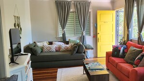 A living room with a sofa, a red couch, a coffee table, and a television.