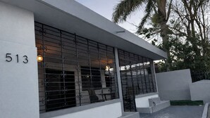 Un edificio moderno con fachada blanca, un letrero con el número '513' y una puerta metálica con diseños decorativos.