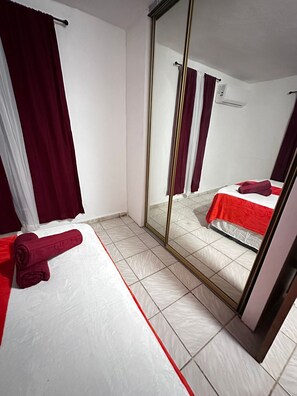 Ein Hotelzimmer mit einem Bett, einem großen Spiegel und einem roten Handtuch auf dem Boden.