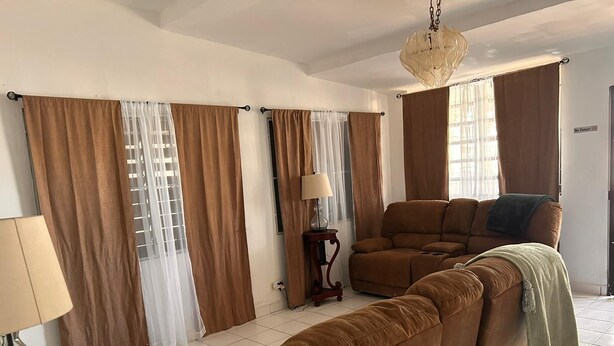 Una sala de estar con un sofá modular, una lámpara y cortinas.