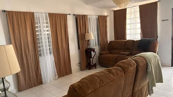 A living room with a sectional sofa, a lamp, and curtains.