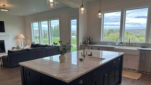 Een moderne keuken met een groot eiland, donkere kastjes en uitzicht op de omgeving.