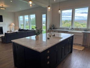 Una cucina moderna con una grande isola, mobili scuri e vista sull'esterno.