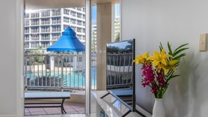 A balcony with a pool view, a blue umbrella, and a vase with flowers. - Moroccan Surfers - 3BR Apartment (Surfers Paradise)