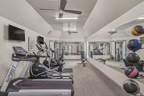 Ein Fitnessraum mit Laufbändern, Krafttrainingsgeräten und Trainingsbällen.