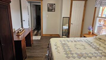 A bedroom with a bed, wooden dresser, and a hallway leading to another room.