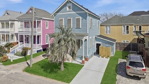 A row of colorful houses with a well-maintained lawn and a parked car. - Sleeps 10, Walk to the Beach and Pleasure Pier in Charming Historic Home (Galveston)