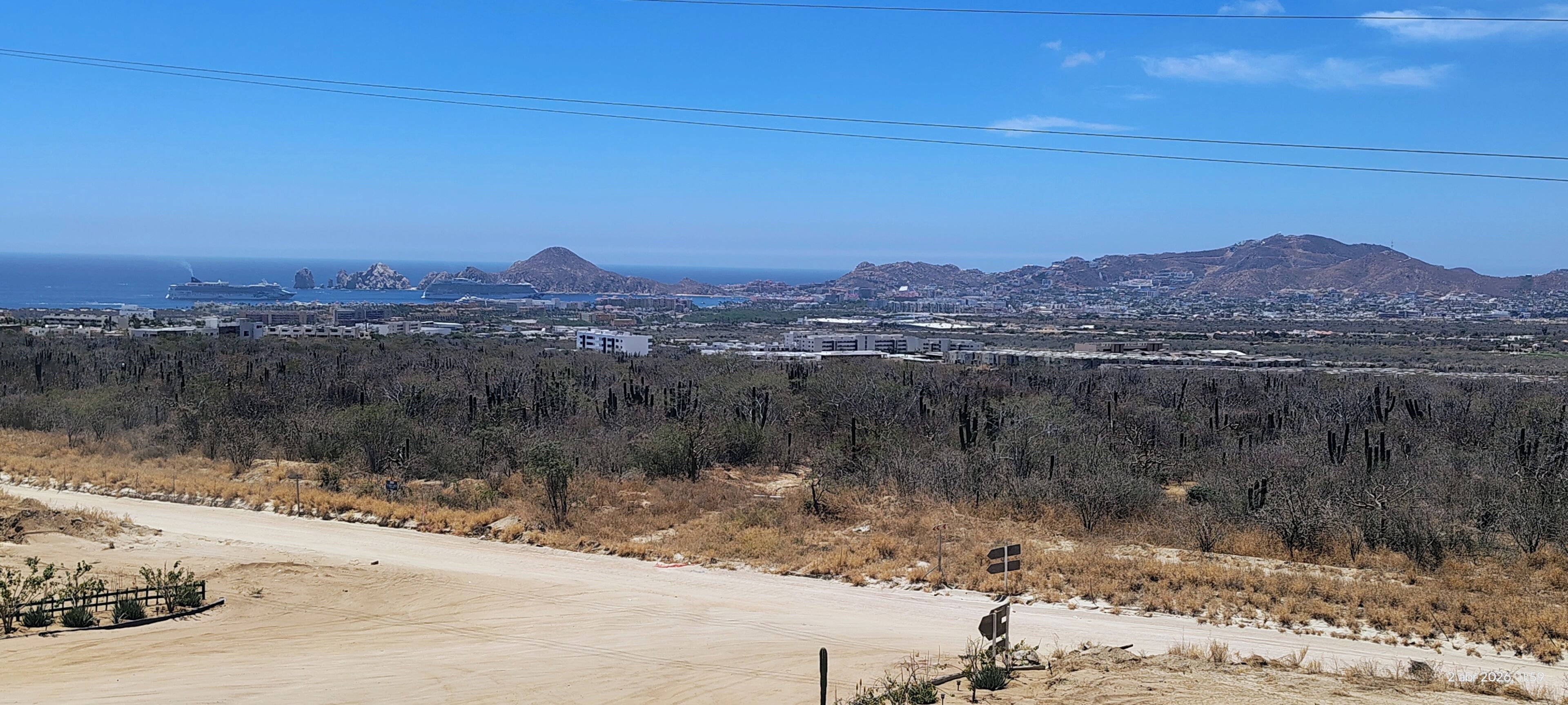 A desert landscape with sparse vegetation, a dirt road, and distant mountains.