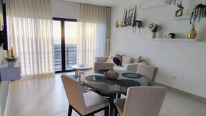 A dining area with a round table, chairs, and a view of a balcony.