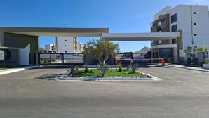 A parking lot with a gated entrance, a building labeled 'CONDOS,' and a clear blue sky.