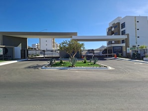 A parking lot with a gated entrance, a building labeled 'CONDOS,' and a clear blue sky. - Adorable 2-bedroom apartment W/AC in Cabo includes a tour to the famous arch (Cabo San Lucas)