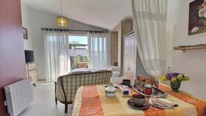 Habitación de hotel con cama, una mesa con cosas para el desayuno, un radiador y una ventana con cortinas.
