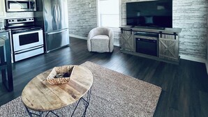 A modern kitchen with stainless steel appliances, a dining area with a wooden table, and a living space with a television and seating. - Kate’s Cottage
cozy 1-bedroom cottage nestled in the woods (Minford)