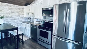A modern kitchen with stainless steel appliances, white cabinetry, and a wooden ceiling. - Kate’s Cottage
cozy 1-bedroom cottage nestled in the woods (Minford)