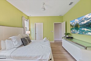 A bedroom with a bed, a nightstand, a painting, and a door leading to another room. - 6BR Themed Villa w/ Game Room+ Pool & Spa Solterra (Davenport)