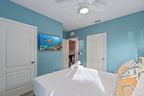 A bedroom with a bed, a ceiling fan, a TV on the wall, and a door leading to another room. - 6BR Themed Villa w/ Game Room+ Pool & Spa Solterra (Davenport)