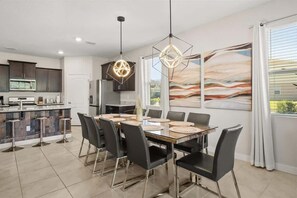 Una cocina moderna con armarios oscuros, una isla central con taburetes e iluminación colgante.