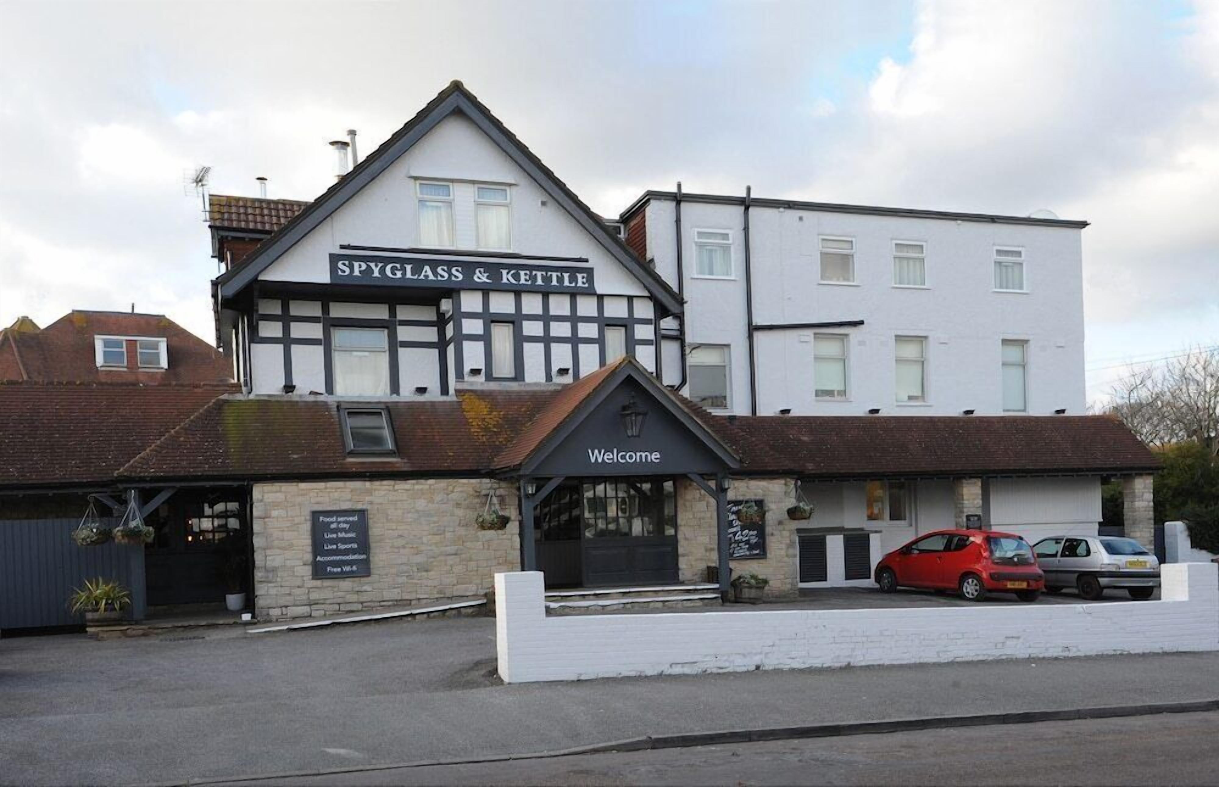 A building with a sign reading 'SPYGLASS & KETTLE' and a 'Welcome' sign.