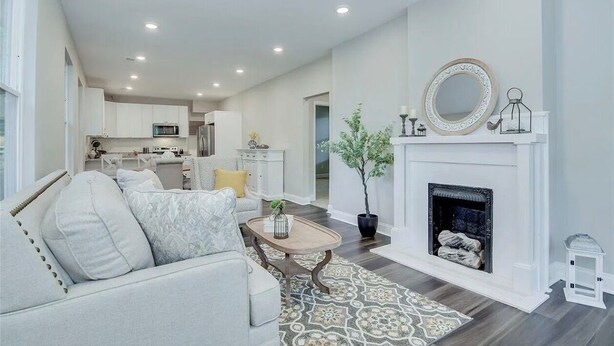 A modern living room with a fireplace, a sofa, a coffee table, and a dining area in the background. - Blue Bungalow! Wonderful 4-bedroom house in charming Augusta (Augusta)