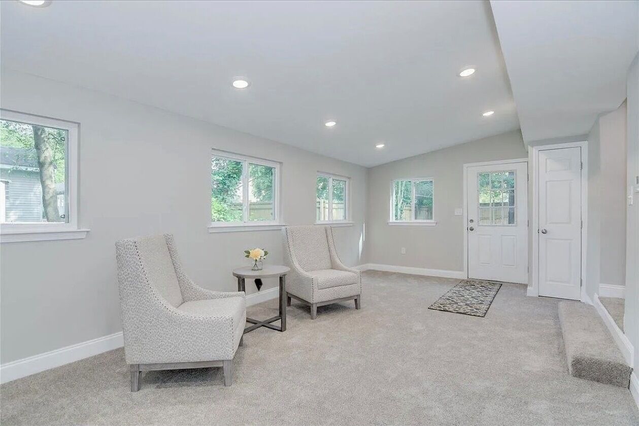 A spacious room with two chairs, a small table, and a door.