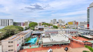 En stadsbild med en blandning av moderna och traditionella byggnader, en järnvägsstation och ett stort, öppet torg med en swimmingpool.