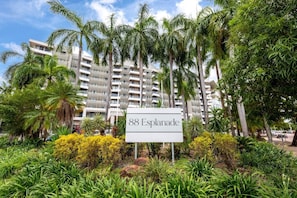 A sign for '88 Esplanade' with a backdrop of a high-rise building and lush greenery. - Resort Style City View w/ King Bed, Pool, Balcony (Darwin City)