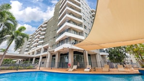 Un hôtel moderne doté d’une piscine, d’un espace extérieur aménagé et d’un grand bâtiment avec des balcons.