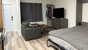 Ein Schlafzimmer mit Bett, Sofa, Fernseher, Kleiderschrank und Schreibtisch.