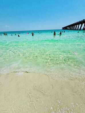 A beach with clear turquoise water, a sandy shore, and a pier in the background. - 4BR 2BA • Beach & Downtown Minutes Away, Boat Parking and Ramp (Gulf Breeze)