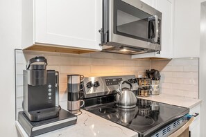 Eine moderne Küche mit einer Keurig-Kaffeemaschine, einem Wasserkocher und einer Mikrowelle.