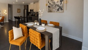 A modern dining area with a dark wood table, orange upholstered chairs, and a minimalist decor. - Chevy Chase  301  2BR (Chevy Chase)