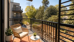 A balcony with a wicker chair, a small table, and a potted plant. - Chevy Chase  301  2BR (Chevy Chase)