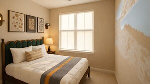 A bedroom with a bed, a nightstand, a lamp, a window, and wall art. - Chevy Chase  301  2BR (Chevy Chase)