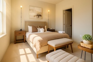 A bedroom with a bed, bedside tables, a bench, a wall-mounted lamp, a framed picture, and a potted plant. - Chevy Chase  315  2BR (Chevy Chase)