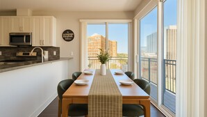 A modern kitchen with white cabinets, a microwave, and a dining area with a table set for four. - Chevy Chase 414 3BR (Chevy Chase)