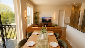 A dining area with a table set for four, a sofa, a TV, and a balcony. - Chevy Chase 414 3BR (Chevy Chase)