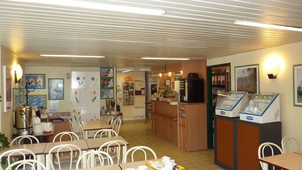 Um restaurante com balcão, mesas, cadeiras e uma vitrine.